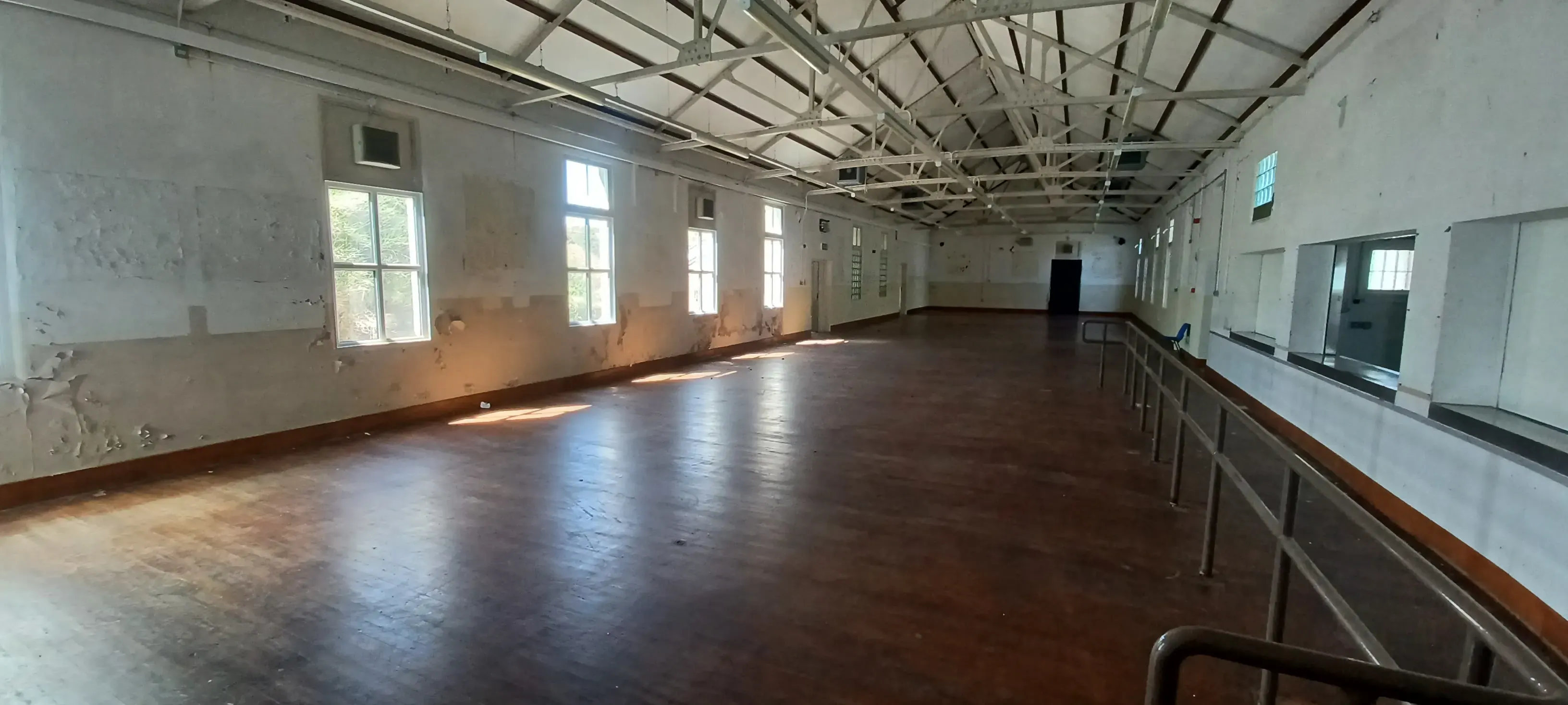 Large hall with wooden floor, exposed roof trusses and tall windows