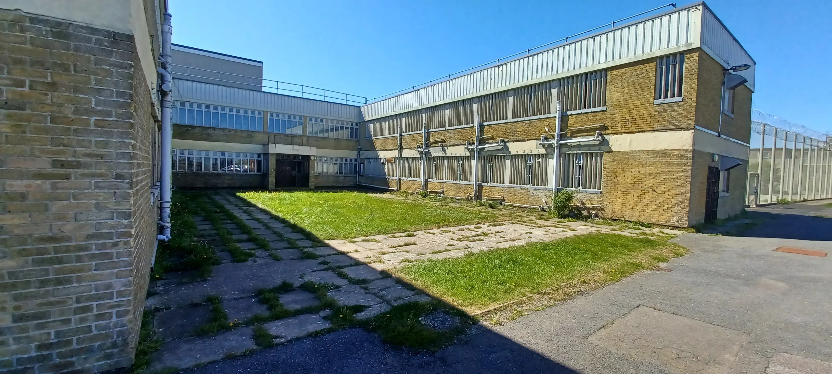 L-shaped brick and metal-clad building around a grass courtyard