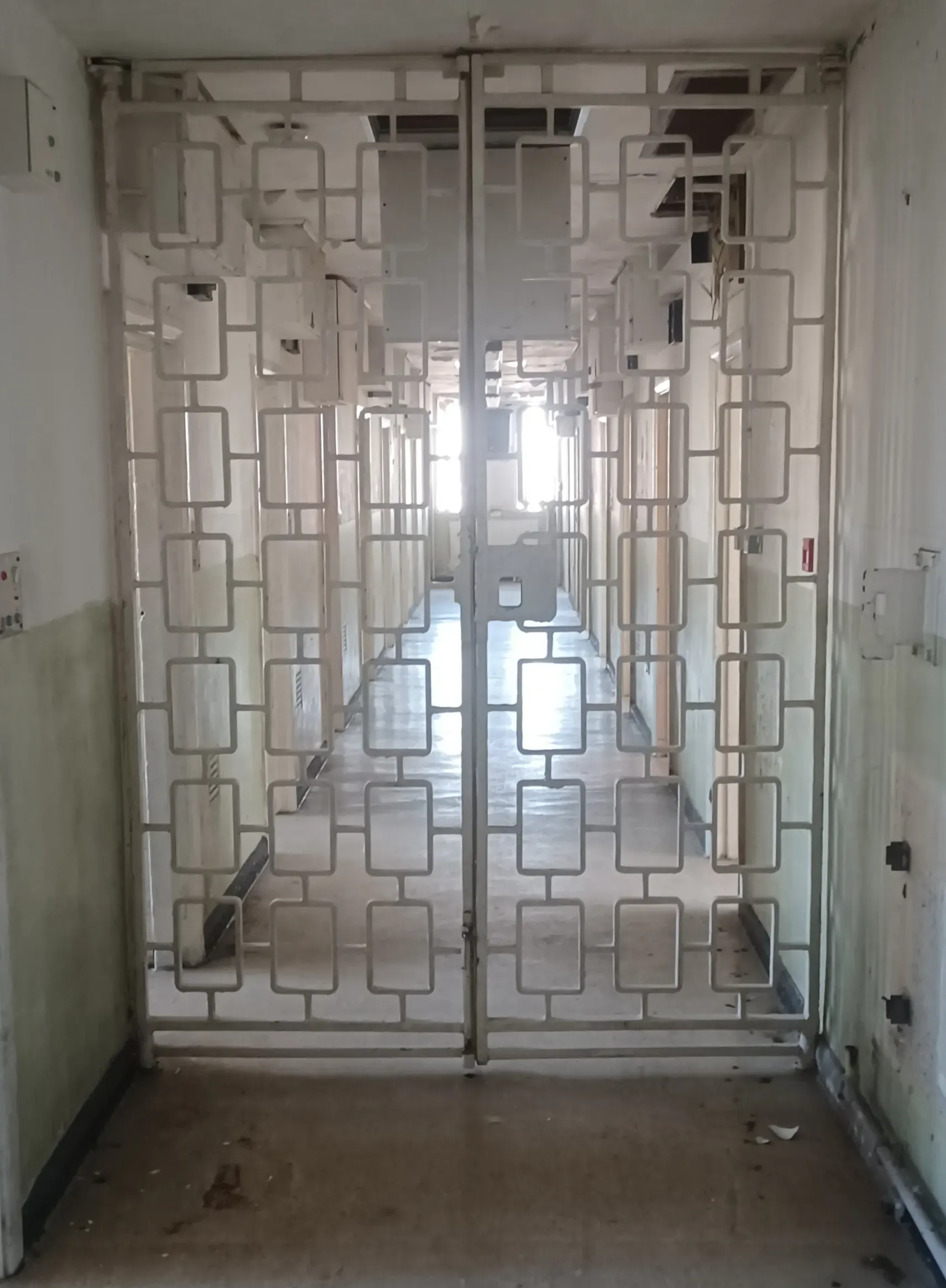 Institutional corridor viewed through a white metal security gate