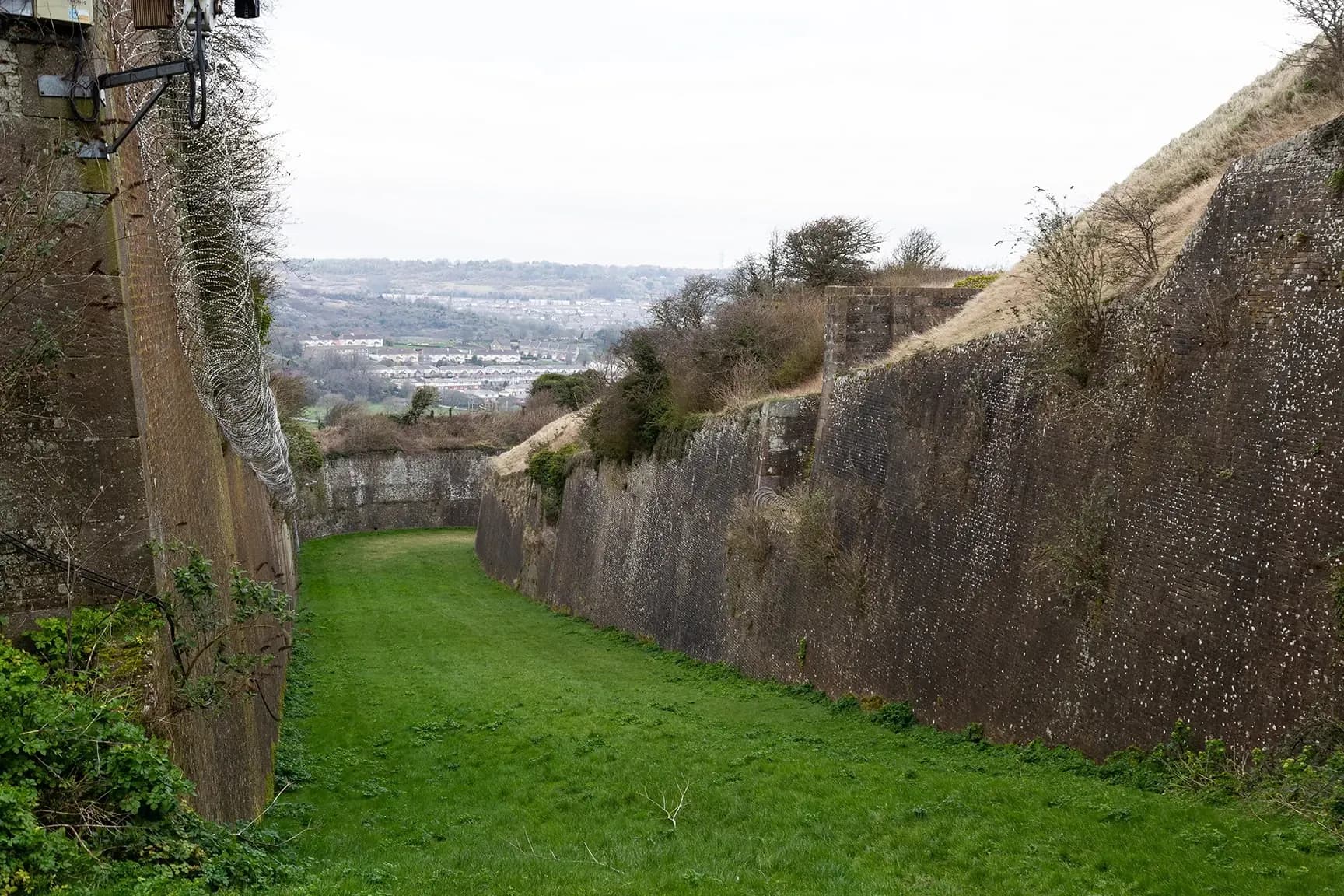 Grassy moat between fortress walls with view across the Dover valley