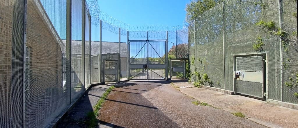 Large mesh security gate topped with concertina wire